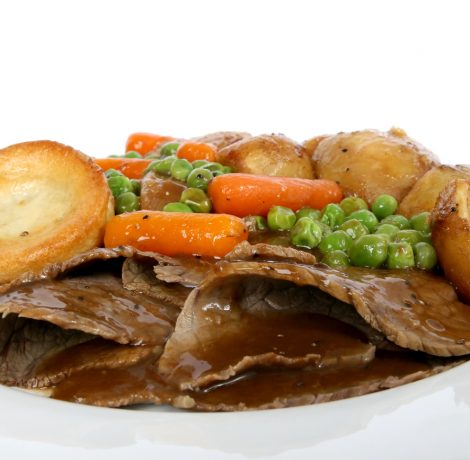 Traditional English Sunday roast with Yorkshire pudding and summer vegetables macro close up isolated on white